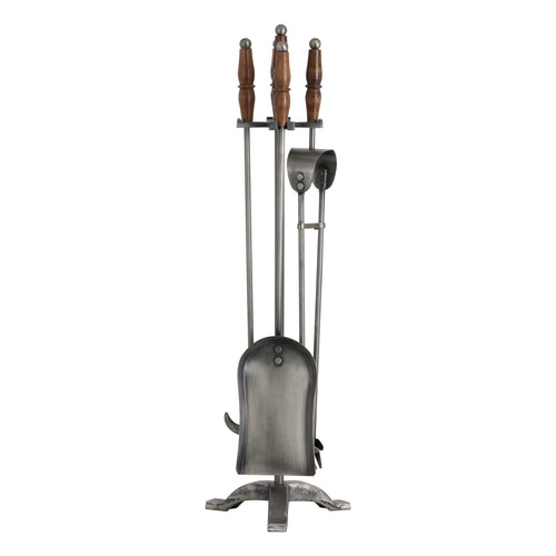 A hand-turned fire companion set in antique pewter with wooden handles, including a pair of tongs, a ladle, and a shovel, displayed on a stand.