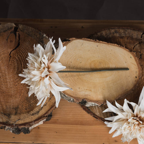 A synthetic cream dahlia flower arrangement placed on a wooden surface.