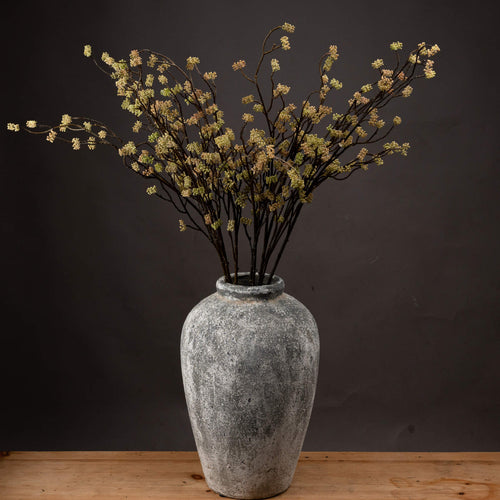 Artificial floral branch in a rustic gray vase against a dark background, depicting the product titled 'Branch in Bloom Filler'.