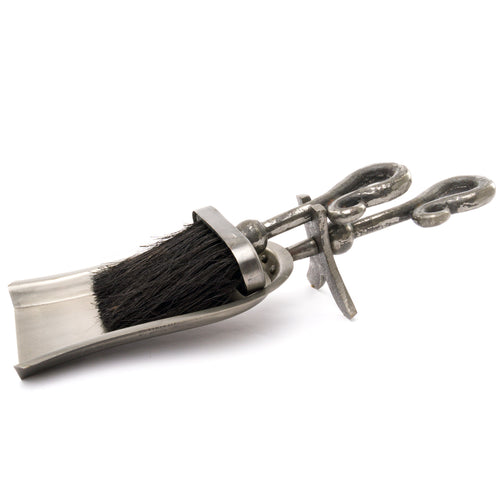 Antique pewter hearth tidy with a crook handle and a brush, displaying an metallic finish.