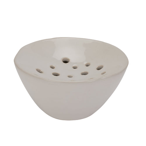 A photo of an off-white ceramic flower frog with a glazed finish and multiple holes on its base for holding floral arrangements.