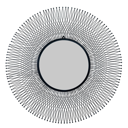 A large circular black wire mirror with an intricate geometric pattern creating a shadow on the walls.