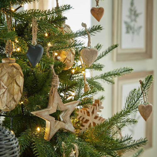 A set of wooden heart-shaped decorations displayed on a Christmas tree, with each heart having a unique wood grain pattern.