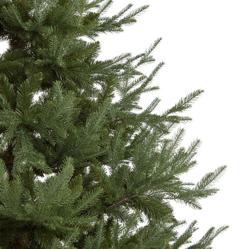 Close-up of a green artificial Christmas tree branch on a white background