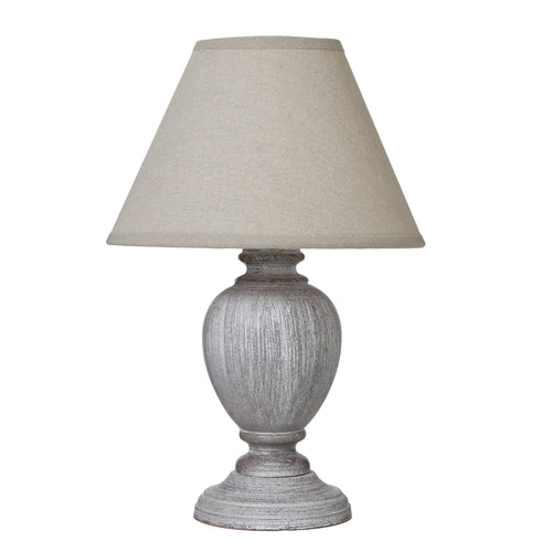 A table lamp with a distressed pewter-toned base and a neutral linen shade.