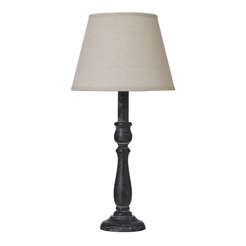 A table lamp with a distressed black base and a beige linen shade.