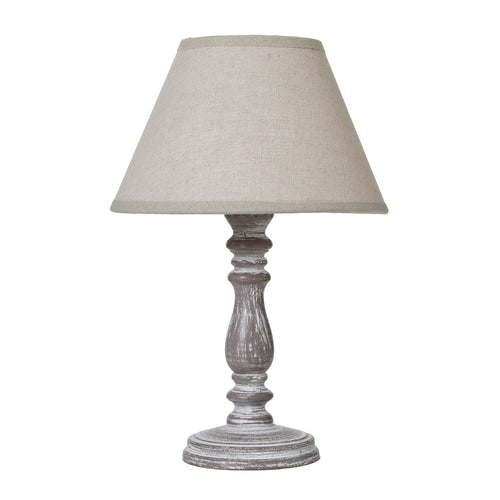 A rustic table lamp with a weathered column base and a natural linen shade.