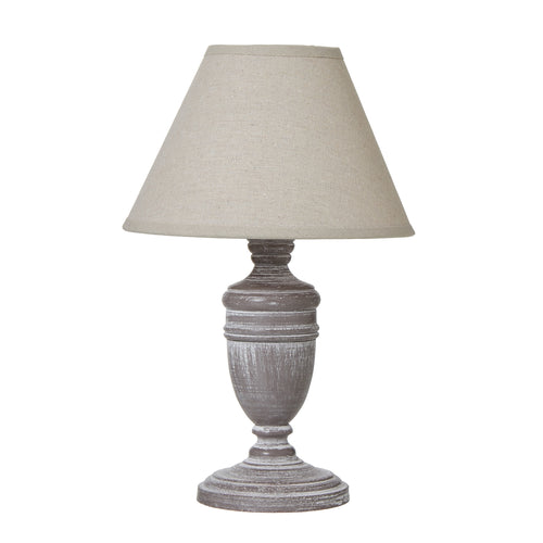 A table lamp with a beige linen shade and a distressed gray urn-shaped base.