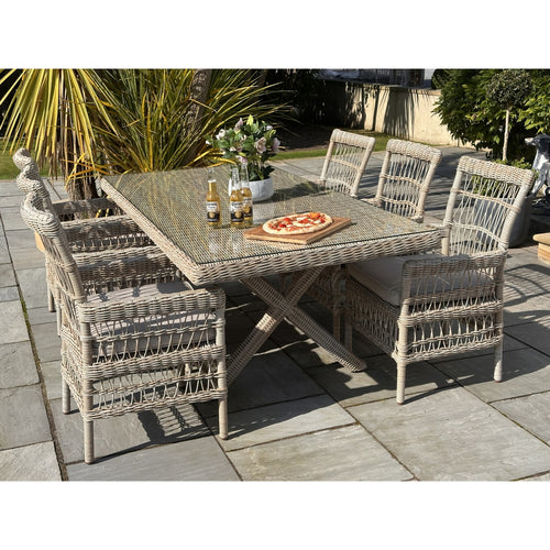 A Provence Collection outdoor 6-seater dining set with a gray rattan table and four chairs, along with a bench, arranged on an outdoor patio.
