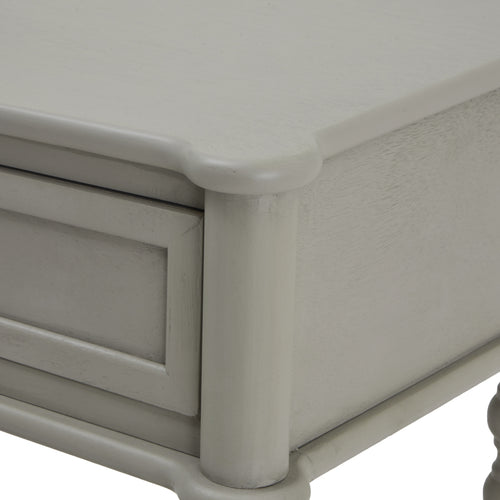Corner of a  gray two-drawer console table with spindle legs and a lower shelf.
