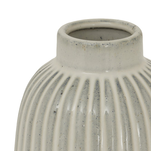 The top of a beige bell-shaped ceramic vase with vertical ridges, narrower at the top and wider at the bottom.
