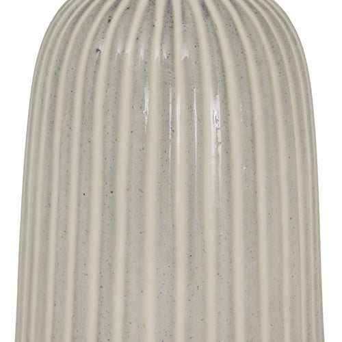 A close up of a beige bell-shaped ceramic vase with vertical ridges, narrower at the top and wider at the bottom. 