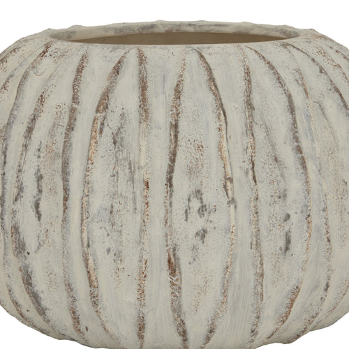 A close up of a beige round vase with a sculpted fin texture