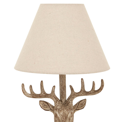 Decorative lamp with deer head design and beige lampshade on a white background