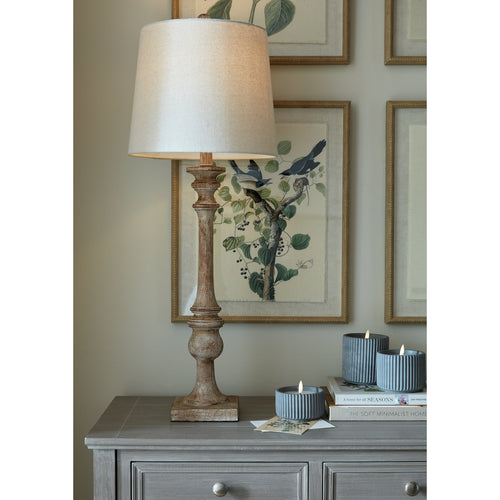 Decorative lamp on a table with framed artwork in the background