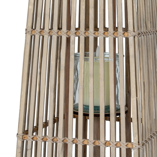 Candle in a glass holder inside a woven wooden basket on a white background